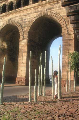 Woman standing near tall stone arches, sculptures.