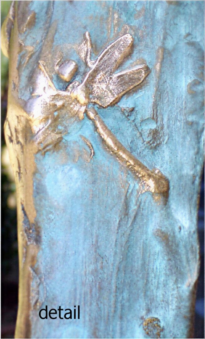 Gold dragonfly sculpture detail on blue surface