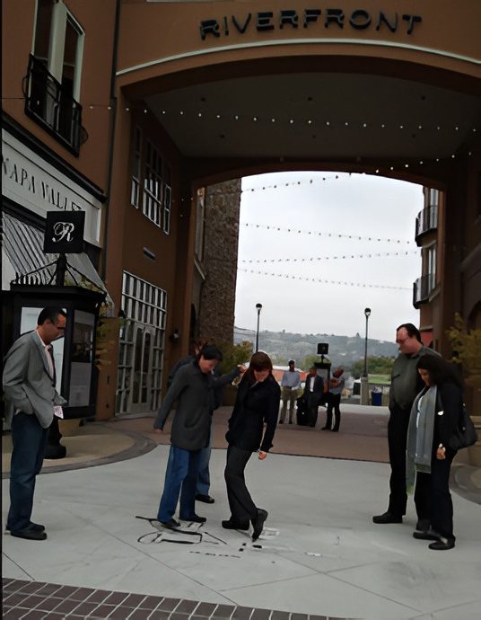 People observing artwork on paved walkway.