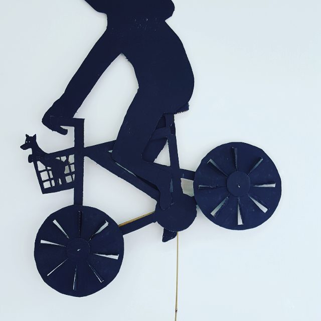 Silhouette of cyclist with dog in basket.