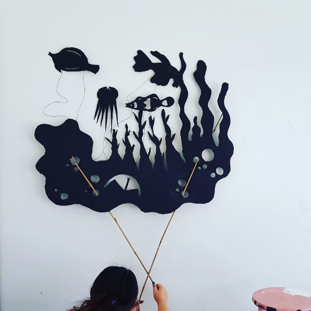 Child playing with ocean-themed shadow puppets.