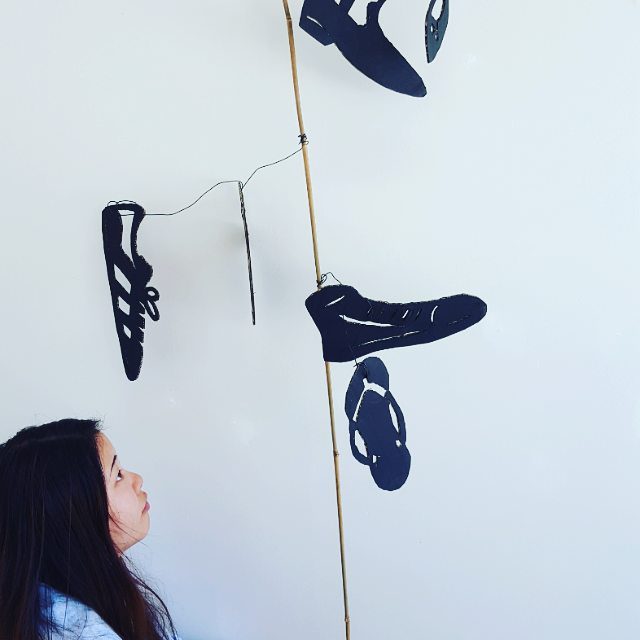 Person looking at hanging shoe cutouts.