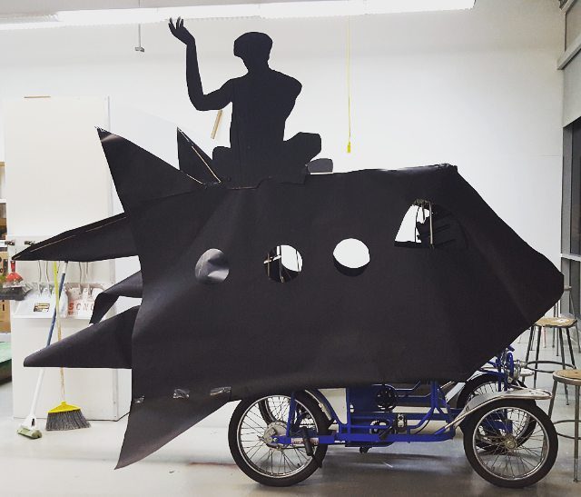 Silhouette figure on bicycle with rocket design.