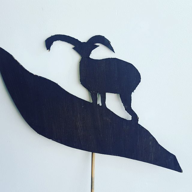 Silhouette of a goat on a hill.