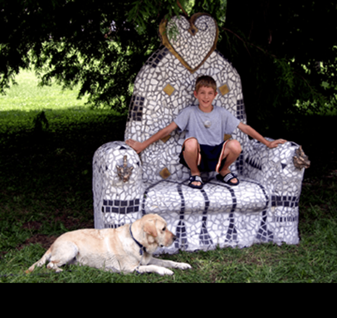 Boy on mosaic chair with Labrador dog.