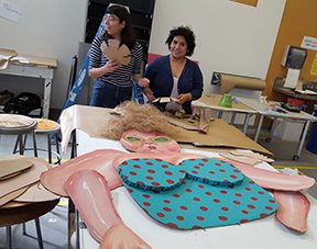Artists creating large colorful paper artwork.