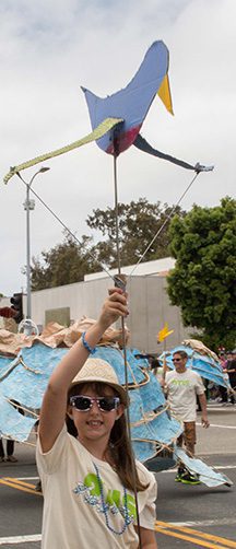 Child holding bird puppet at parade.