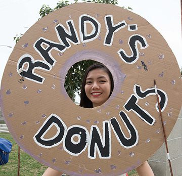 Person smiling through donut-shaped sign.