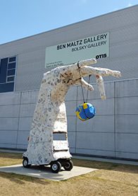 Sculpture of hand holding globe outside gallery.