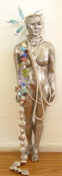 Metallic statue adorned with shells and beads.