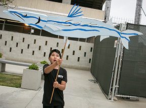 Child holding a large fish-shaped kite.