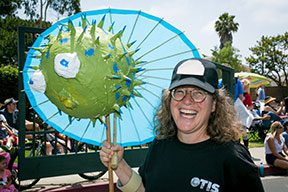 Smiling person holding colorful parasol art.