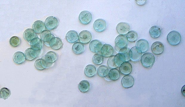 Green glass tokens scattered on white surface.