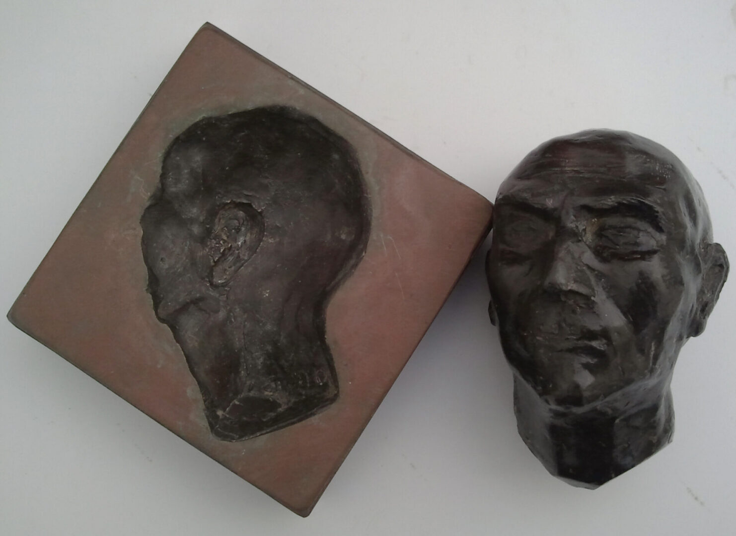 Bronze head sculpture with matching relief plaque.