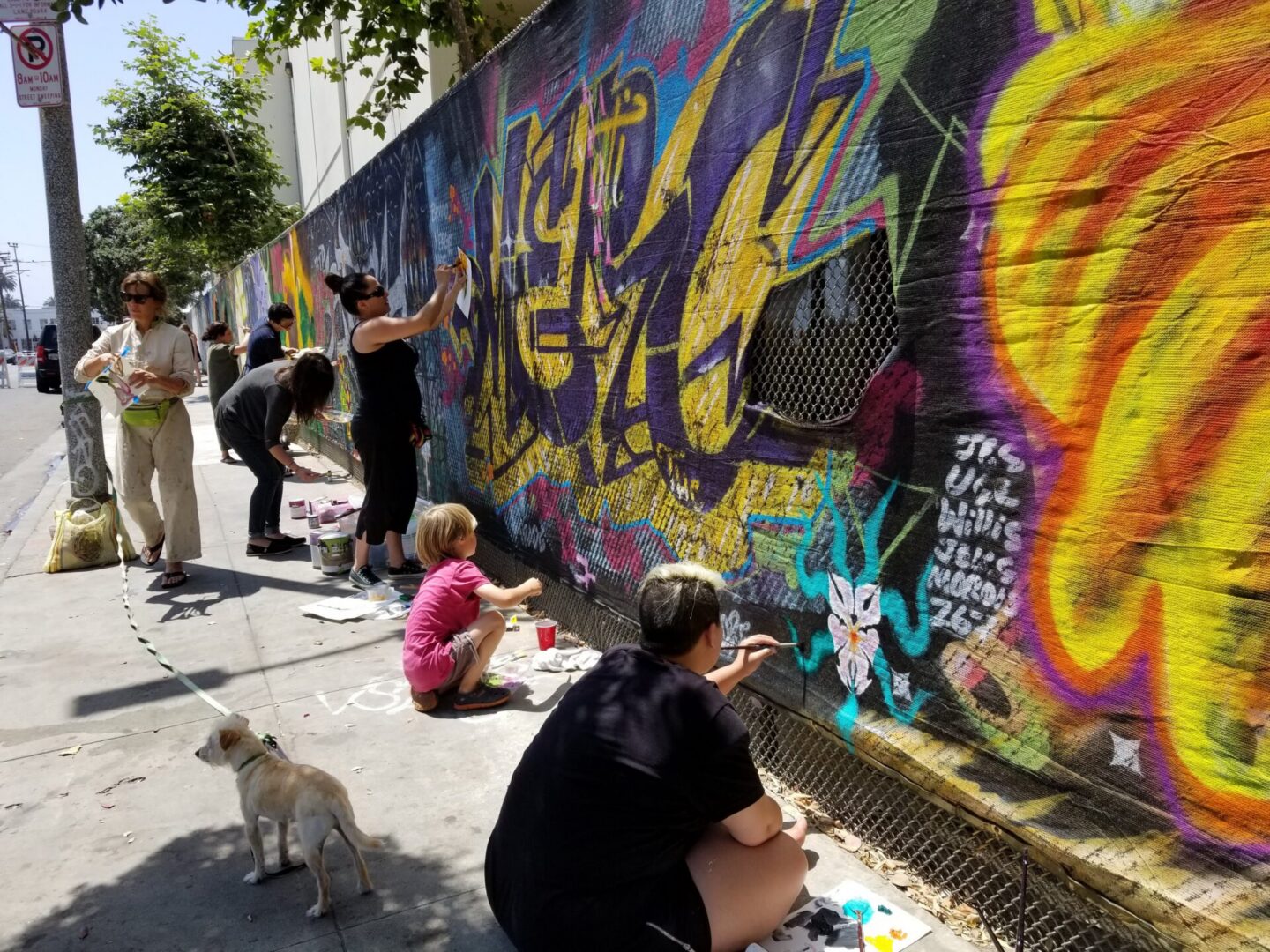 People painting graffiti on a sunny street.