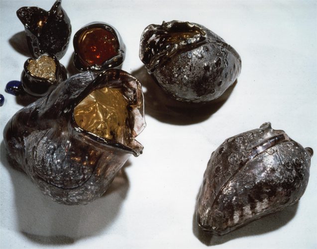 Dark, textured glass vessels on white surface.
