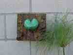Heart-shaped object and plant on wall.