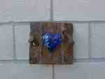 Blue heart on rustic wooden plaque.