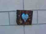 Blue heart painted on brick wall.