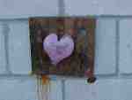 Pink heart graffiti on brick wall.