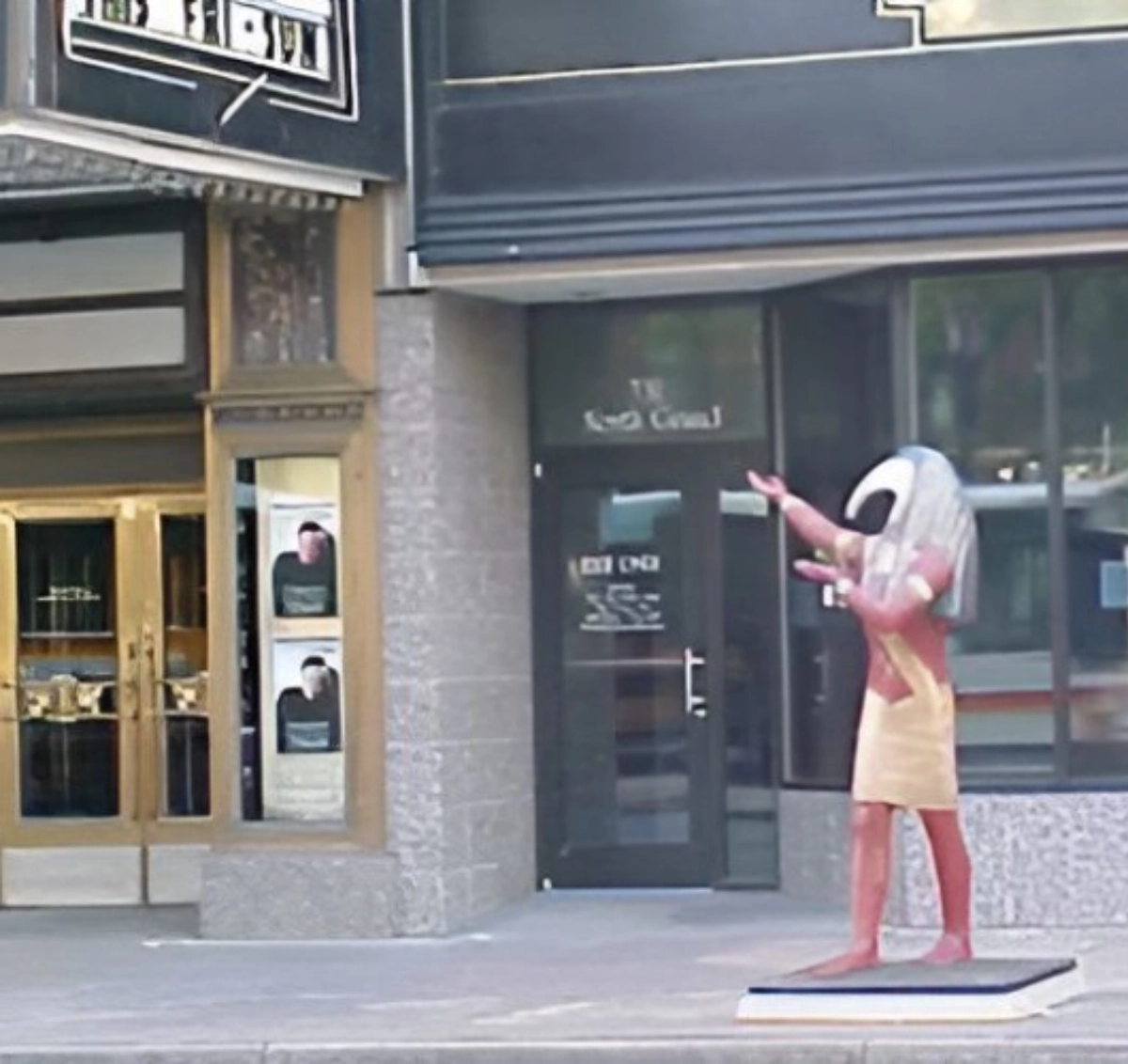 Egyptian statue displayed outside a building entrance.