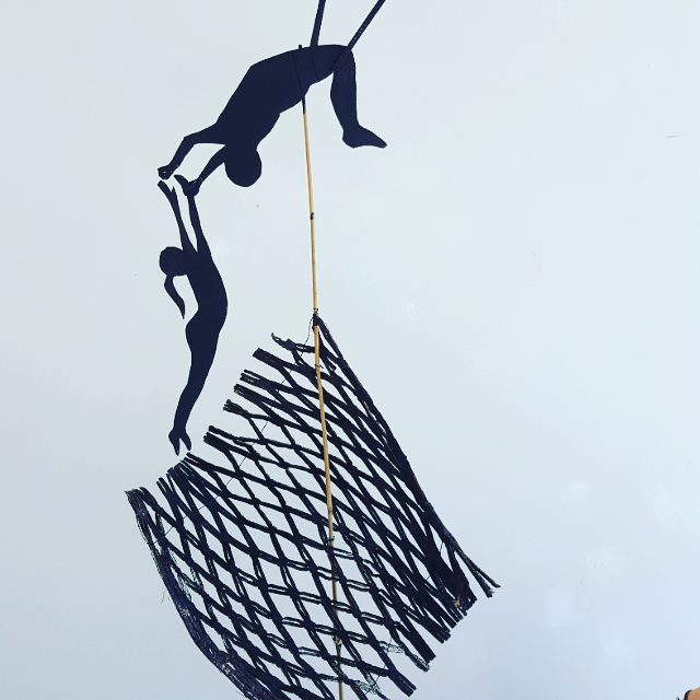 Silhouetted figures climbing a net structure.