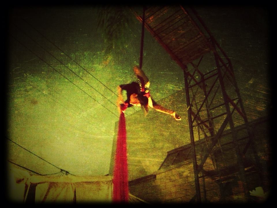 Aerial performer on red silk at night.