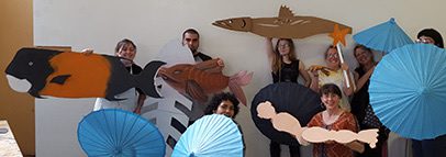 People holding fish cutouts and blue parasols.