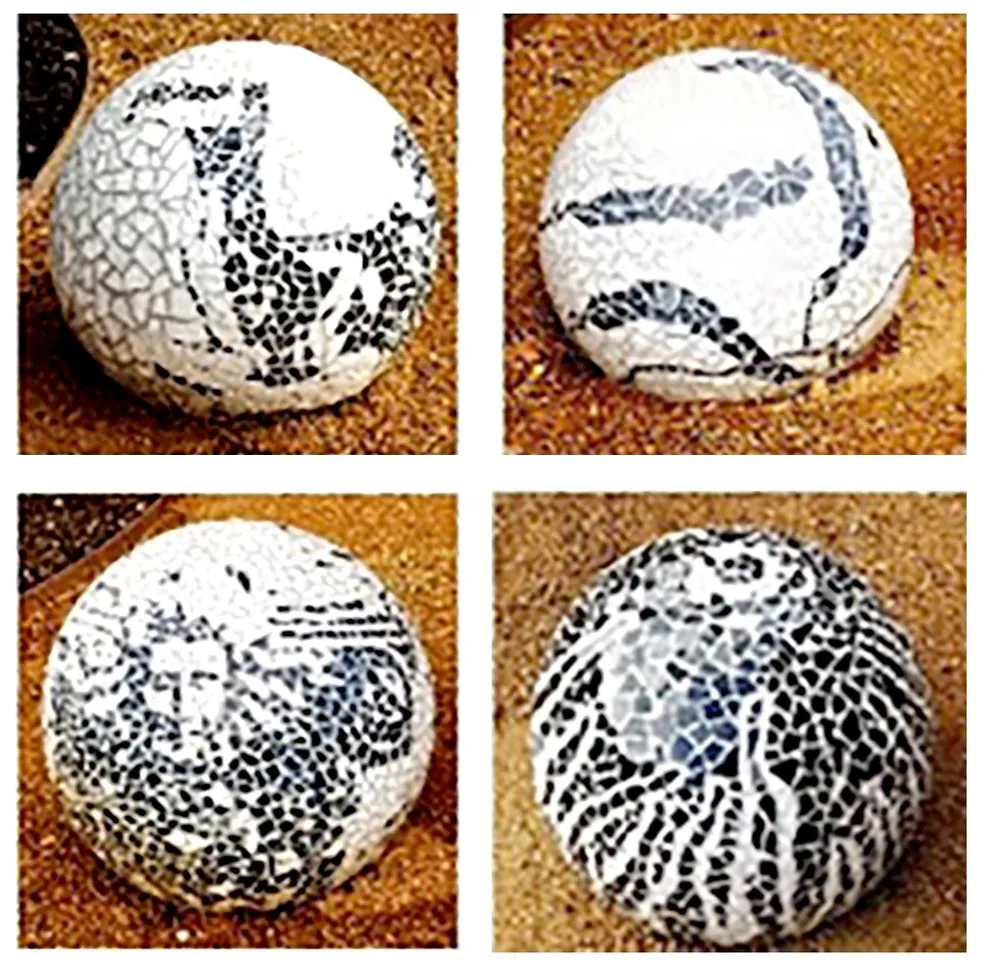Mosaic-patterned spheres on sandy surface.