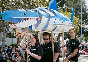 People carrying large paper shark in parade.
