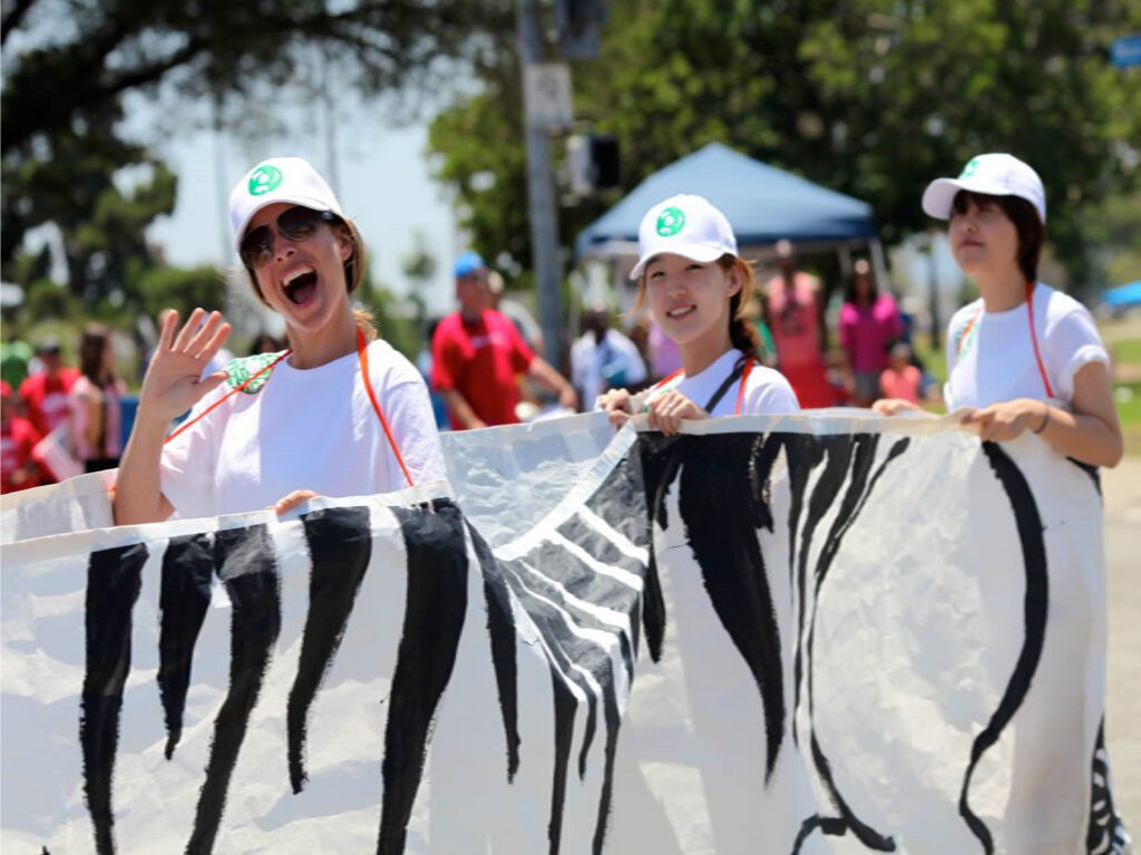 People holding a banner at outdoor event.