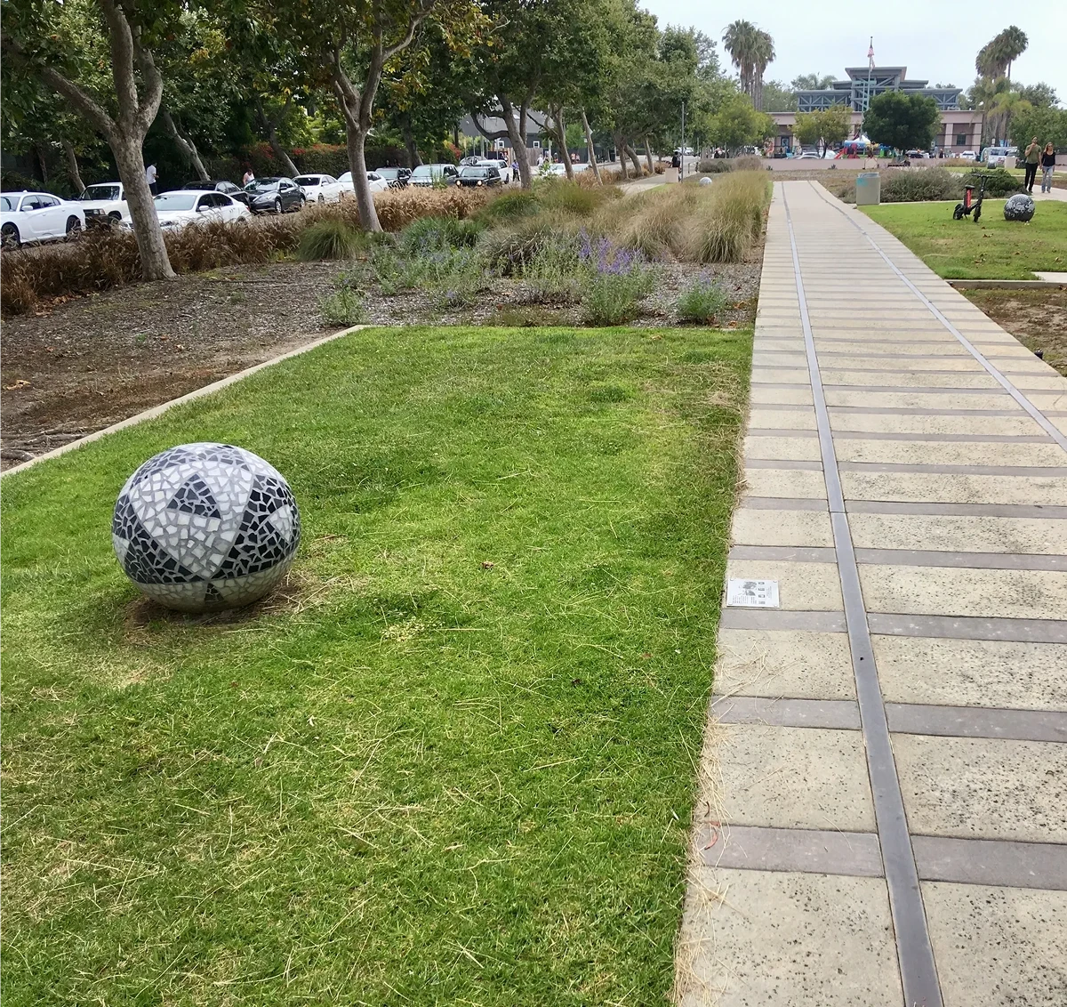 Pathway beside grass with decorative stone sphere.