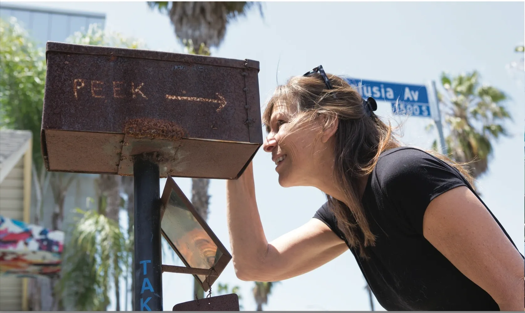 Woman peeking into outdoor metal box.