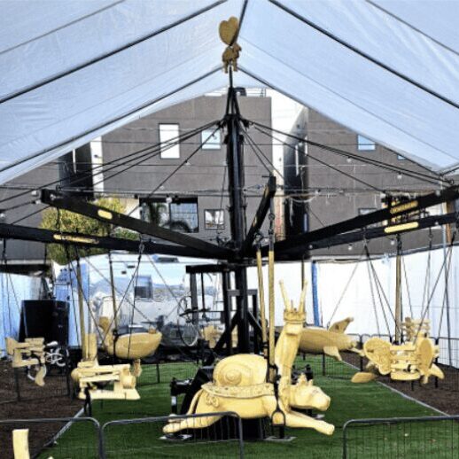 Carousel with animal-shaped seats under tent.