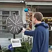 Person spinning wheel outside a store.