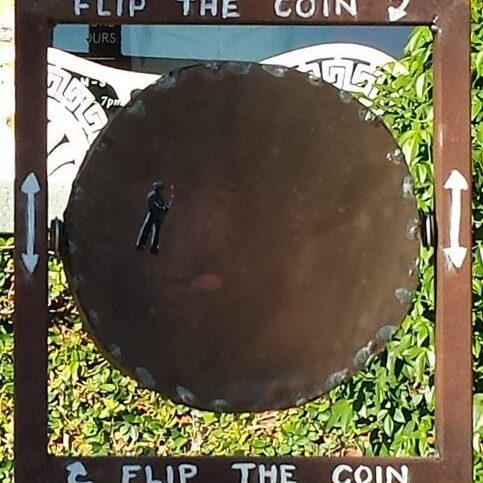 Metal sign with "Flip the Coin" text.
