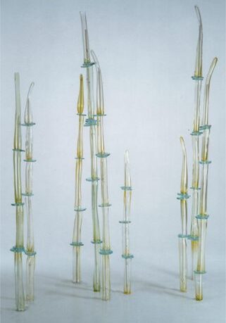 Glass sculpture installation with tall, slender shapes.