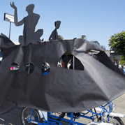 Bicycle float with abstract figures in parade.