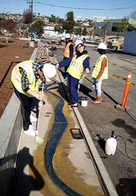 Workers painting design on concrete channel.