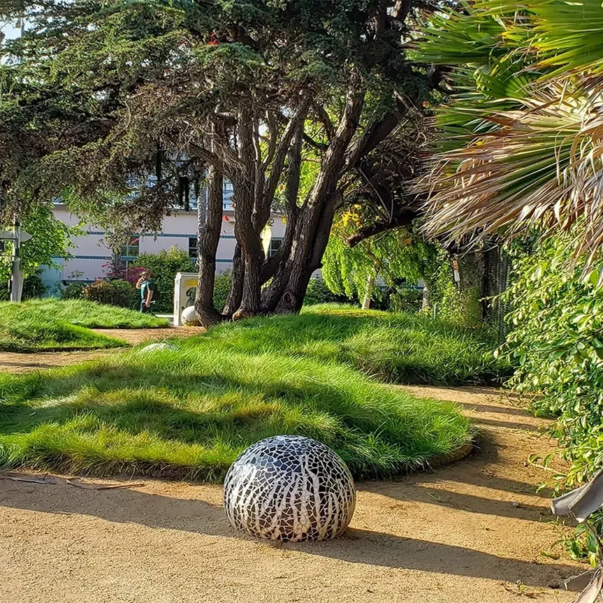 Garden path with trees and decorative sphere.